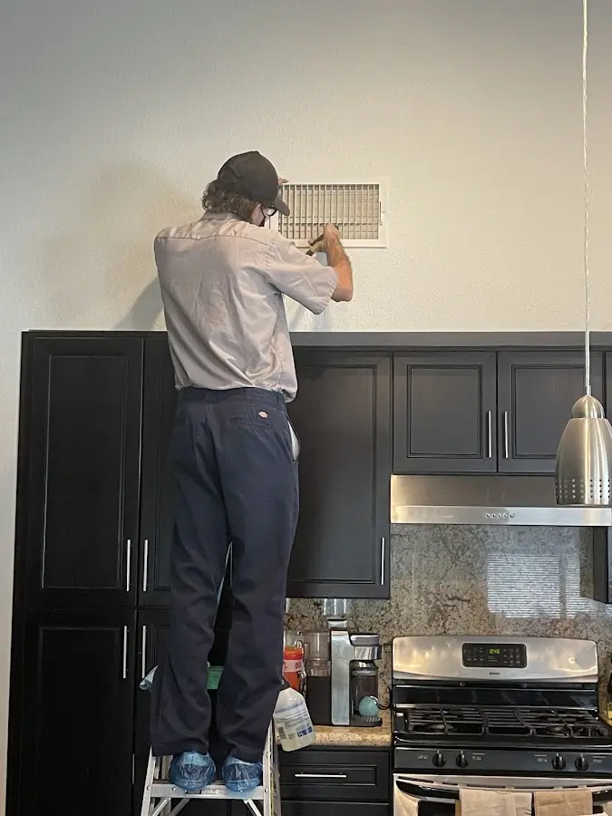 Technician inspecting an air vent during HVAC service in Hasbrouck Heights